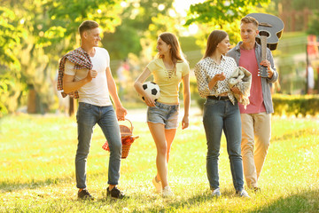 Young people with picnic basket in park on summer day