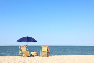 Fototapeta na wymiar Empty wooden sunbeds and beach accessories on sandy shore