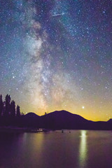 A Night time Astrophotograph of Meteorite Slicing Through the Milky Way above a Mountain Lake