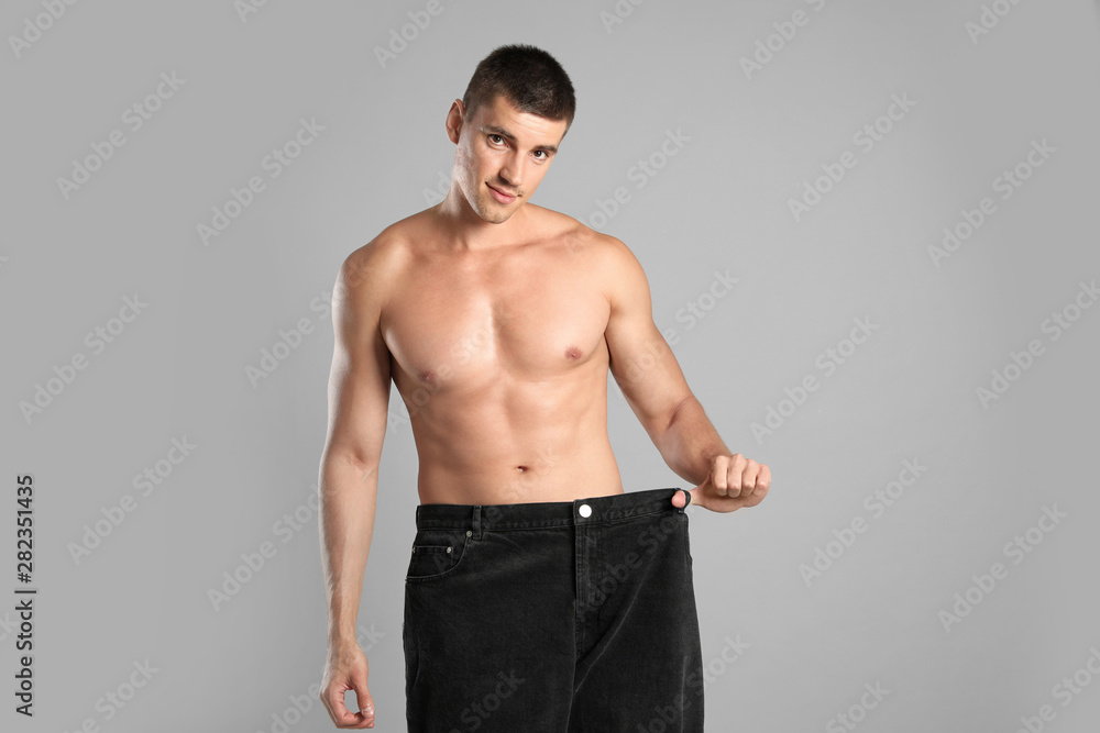 Poster Young man with slim body in old big size jeans on grey background