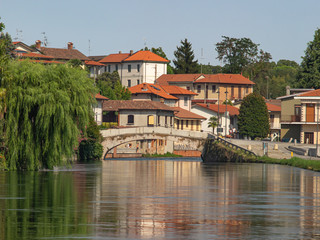 Fototapeta premium landscape on the outskirts of Milan, a colorful village is reflected in the navigable canal of the Naviglio Grande.Italy