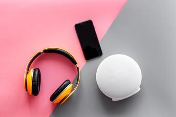 portable wireless speakers, phone and headphones for music listening on pink and gray background...