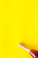 Champagne bottle for celebration on yellow background top view mock up