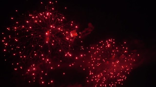 Multiple red and white fireworks burst in the night sky.