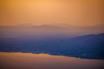 Natural panoramic wallpaper of high mountain scenery, overlooking the atmosphere of rivers, grasslands, roads, and the orange sunshine in the evening, blown through blurred cool air.