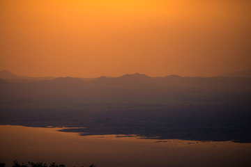 Obraz premium Natural panoramic wallpaper of high mountain scenery, overlooking the atmosphere of rivers, grasslands, roads, and the orange sunshine in the evening, blown through blurred cool air.