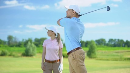 Man in sportswear hitting ball female partner rejoicing golf game victory, sport