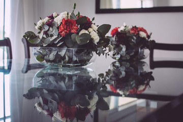 Bouquets of white and red flowers on a glass table with antique wooden chairs. Interior design.