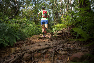 Woman ultra marathon runner running on tropical rainforest trail