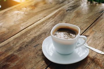 The ceramic cup of hot cappuccino coffee on the wooden table in the restaurant or coffee shop. natural light. morning hot drink cafe shop.