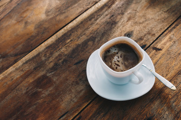 The ceramic cup of hot cappuccino coffee on the wooden table in the restaurant or coffee shop. natural light. morning hot drink cafe shop.