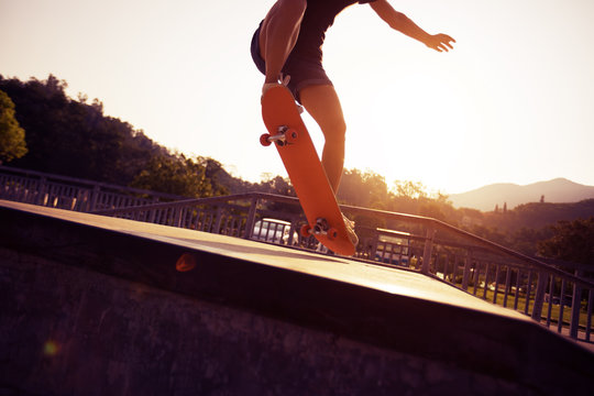 Skateboarder doing ollie at sunrise skatepark ramp