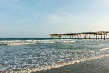 Fototapeta na wymiar Pier into the Atlantic Ocean, Sunset Beach, North Carolina; with copy space for text, at sunrise