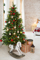 Classic Christmass or New Year decoration in a bedroom. Toy horse, spruce, classic decorations. Vintage New Year decore. Christmas mood in children room