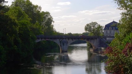 Traffic cars passing Rue de Saintes bridge, over the Charente river, at Angouleme. Beautiful sunset lighting. Establishing shot.