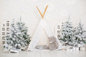 White children room with christmas decorations. Slylish wooden decorative Christmas-tree with inscription 'Noel'. Playroom for kids in white colors. Stylish Christmas interior