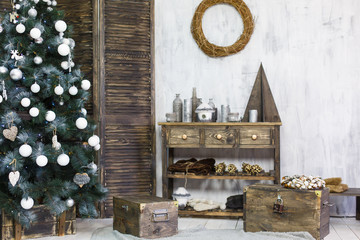 Ascetic scandinavian interior decorated for New Year Holidays. Wooden chest and commode near the Christmas tree