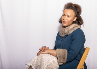 Young Afro American lady sitting and standing in and elegant  fashion photo shoot with cell phone enjoying herself 