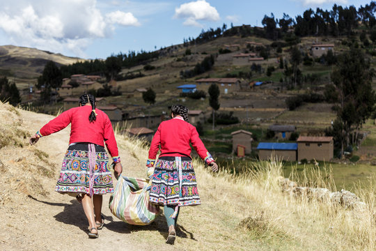 A couple of woman carry a sack of potatoes to share in your community