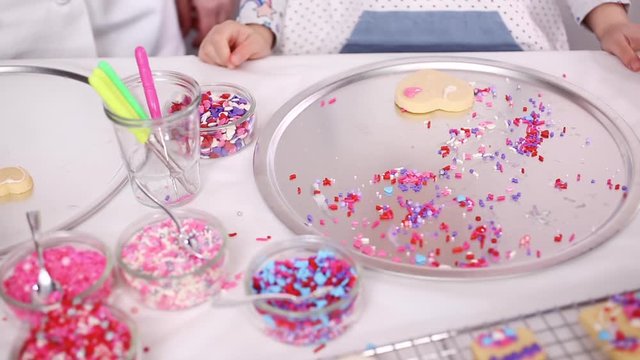 Time lapse. Step by step. Decorating sugar cookies with royal icing and sprinkles for Valentine's day.