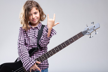 Fototapeta premium Smiling girl playing guitar giving a horns sign