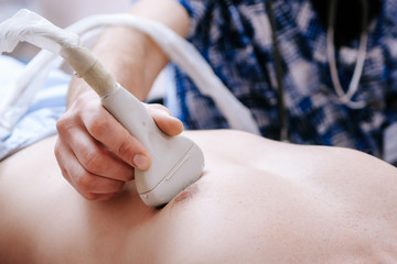 The doctor holds an ultrasound machine on his chest. Checking the heart of a patient in a hospital office