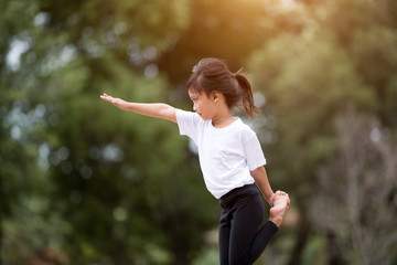 beautiful little asian child girl doing yoga in the public park.
