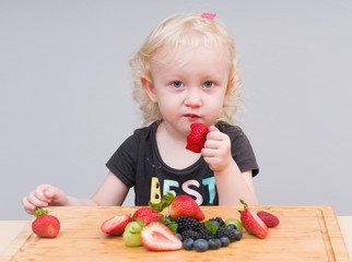 Little girl eating strawberry 