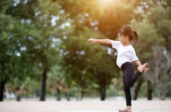 beautiful little asian child girl doing yoga in the public park.