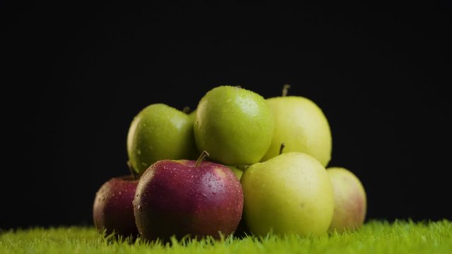Bunch of Green and Red fresh Apples on Grass against Black Background