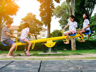 Happy Asian children playing seesaw board together in the park outdoor, lifestyle concept.
