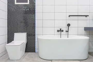 Modern bathroom interior with minimalistic shower and lighting, white toilet, sink and bathtub