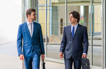 Confident business men talking in front of modern office building. Businessman and his colleague. Banking and financial market.
