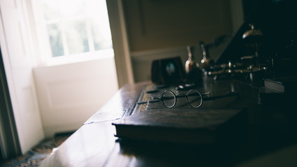 Vintage eyeglasses on a desk next to other antique objects in a residential study room