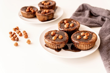 Homemade chocolate muffins with topping and walnuts on white table