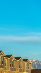 Vertical frame Townhomes against snow topped mountain and bright blue sky on a sunny day