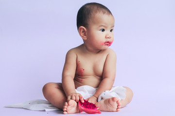 asian cute baby girl eating red dragon fruit. newborn baby on white background