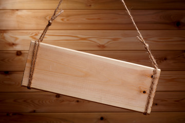 Wooden signboard on a rough rope on a beautiful wooden background