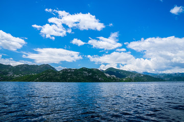 Montenegro, Green mountains alongside coast of lakeside of skadar lake waters viewed from boat in national park
