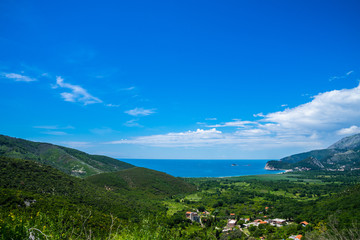 Fototapeta na wymiar Montenegro, View above green bay and beach of petrovac in budva municipality with blue sky in summer holiday