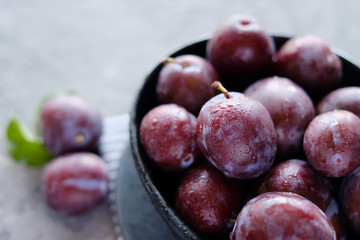 Fresh violet plums at dark wooden table background