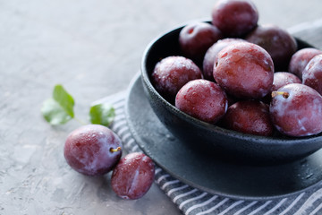 Fresh violet plums at dark wooden table background