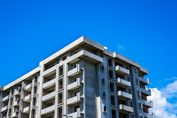 Building shell made of concrete of a huge apartment building with many accomodations under blue sky