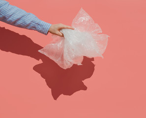 Zero waste lifestyle concept.  A hand holding plastic disposable bags. Pink background, pop art.