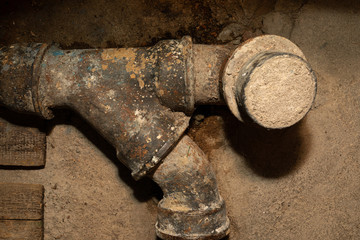 Worn out rusty water pipe in a concrete wall