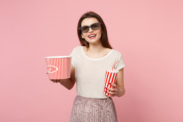 Cheerful young woman in 3d imax glasses posing isolated on pastel pink background. People sincere emotions in cinema, lifestyle concept. Mock up copy space. Hold bucket of popcorn cup of cola or soda.