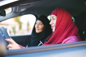 Two muslim women inside a car - mother and daughter traveling together - islamic women only taxi driver