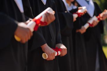 Young graduates holding their new masters diplomas.