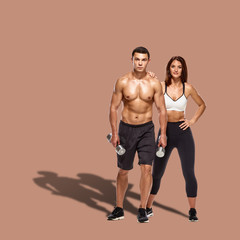 Fototapeta na wymiar Healthy couple with dumbbells on brown background with shadow on floor