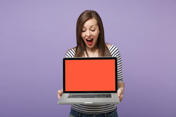 Naklejka premium Young brunette woman girl in casual striped clothes posing isolated on violet purple background studio portrait. People sincere emotions lifestyle concept. Mock up copy space. Hold tablet pc computer.